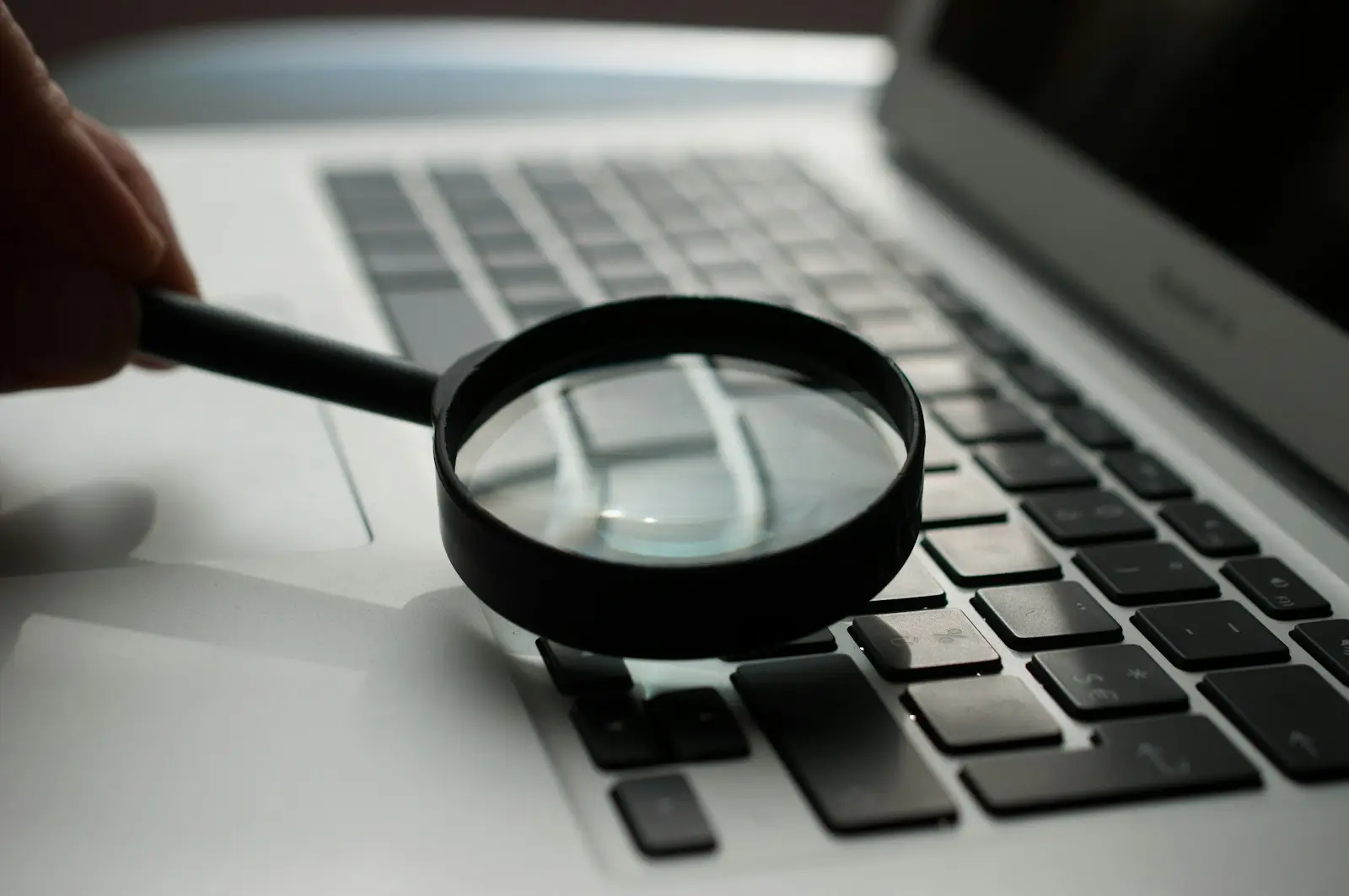 A magnifying glass resting next to a laptop
